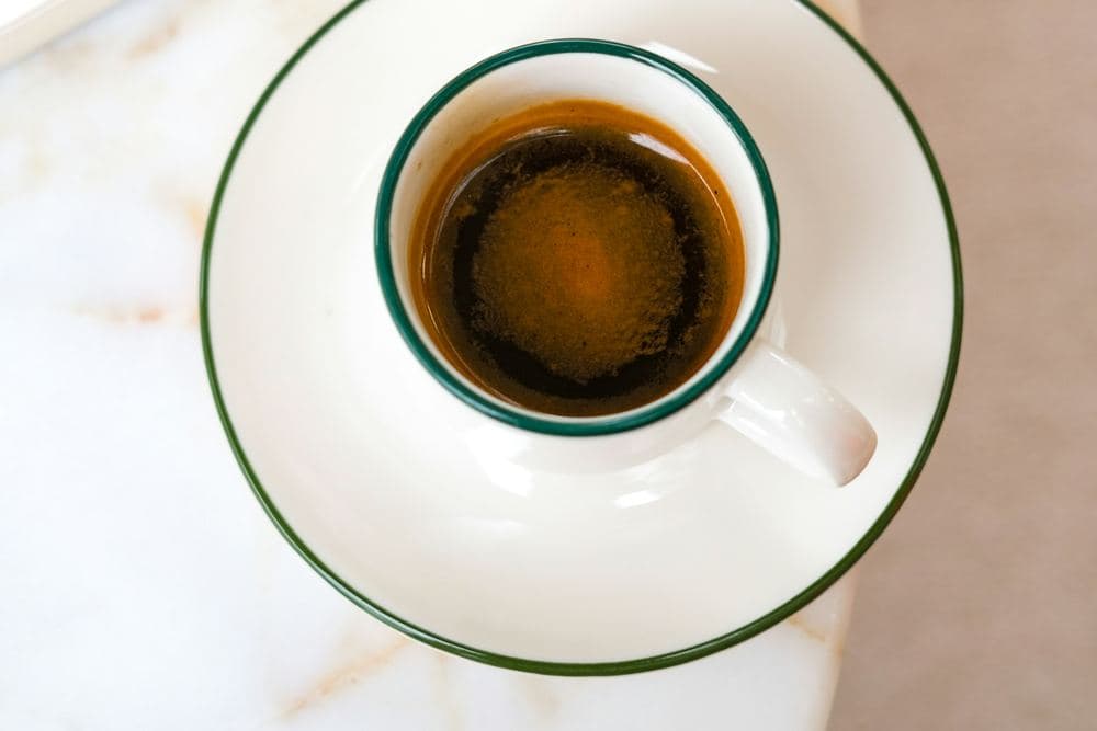 Taza de café solo sobre una mesa de mármol claro con vetas doradas