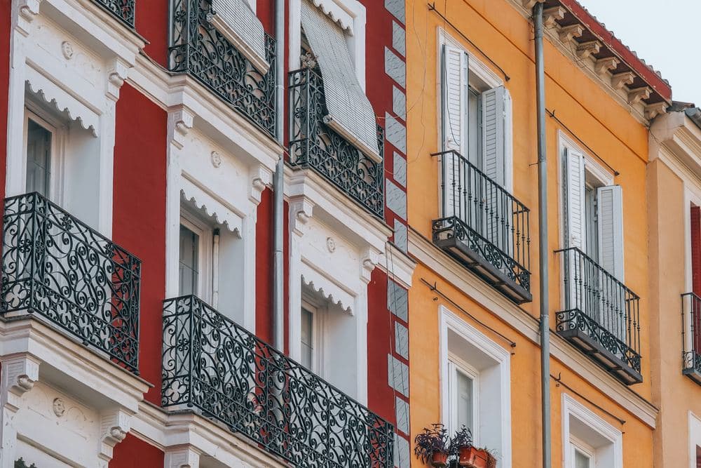 Fachadas madrileñas de colores con balcones de forja y contraventanas
